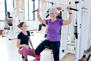 Ældre dame hos Fysisk Form, der får hjælp til træningen af en personlig træning.